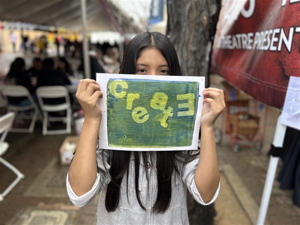 Student holding artwork saying create